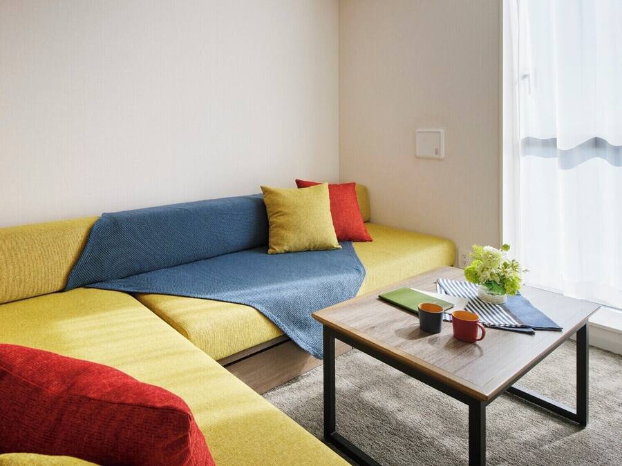 Un saló modern amb un sofà, una taula de centre i una finestra amb cortines.