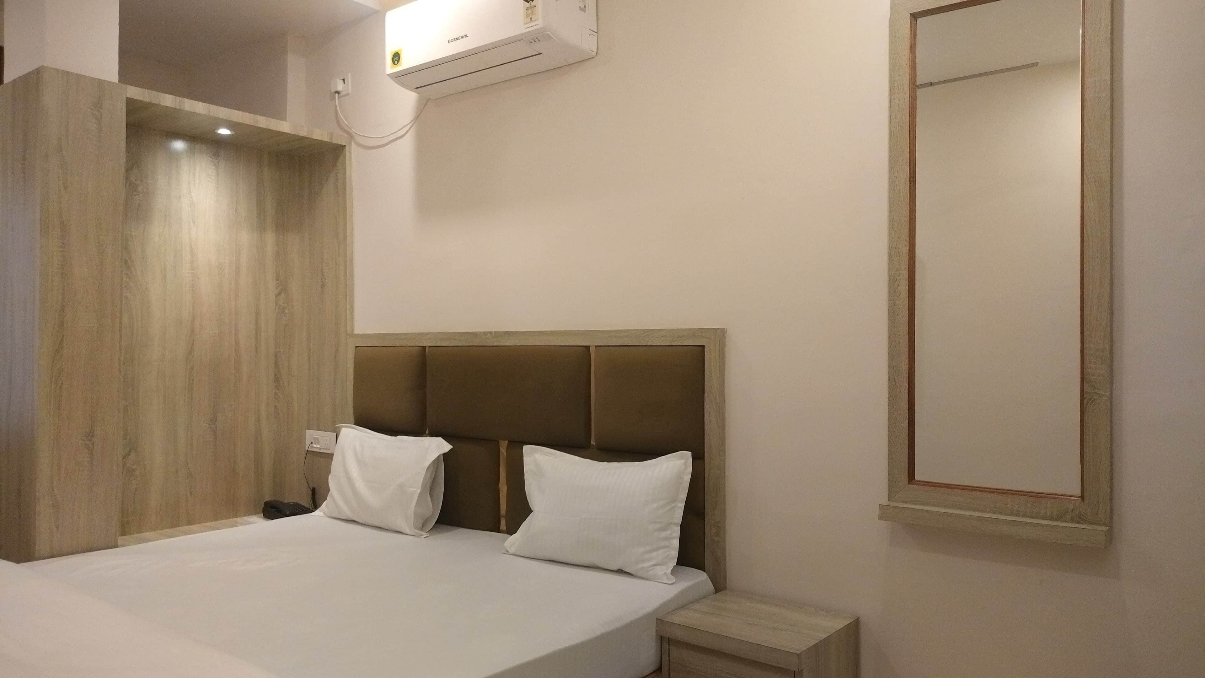Une chambre d’hôtel équipée d’un lit, d’une table de chevet et d’un climatiseur fixé au mur.