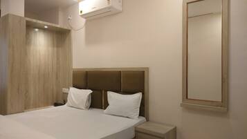 Una habitación de hotel con una cama, una mesita de noche y un aire acondicionado instalado en la pared.