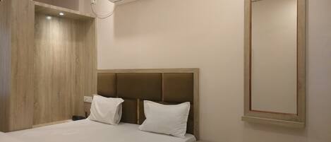 Une chambre d’hôtel équipée d’un lit, d’une table de chevet et d’un climatiseur fixé au mur.