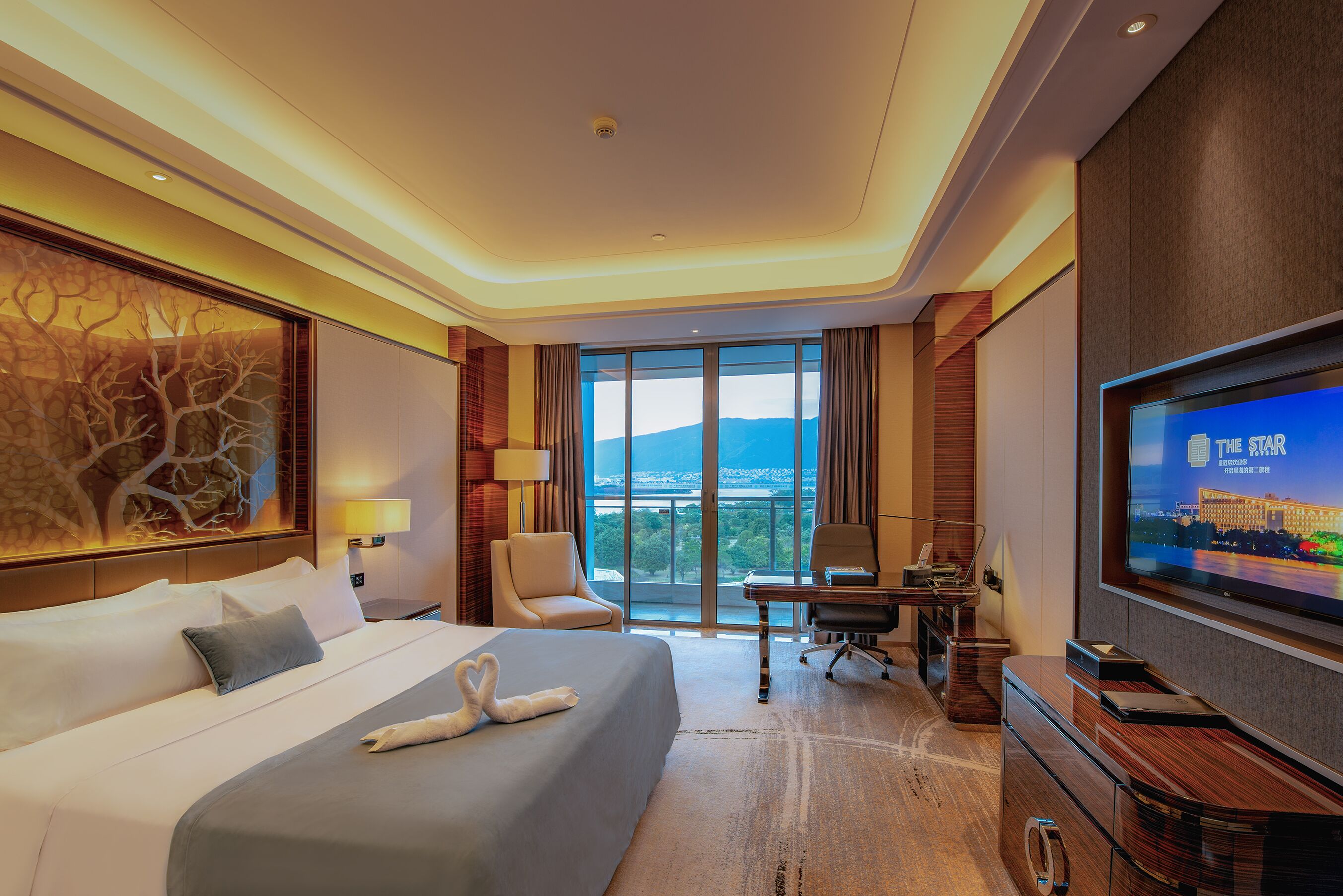 Quarto de hotel com cama grande, escrivaninha, televisão e vista para a cidade.