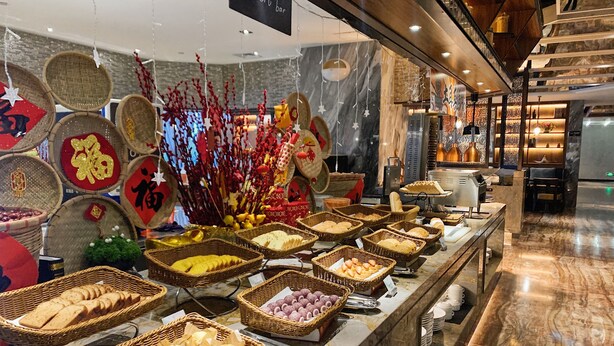A buffet area with various food items displayed in baskets, a sign indicating a dessert bar, and a marble floor. - the Star Hotel (Zhaoqing)