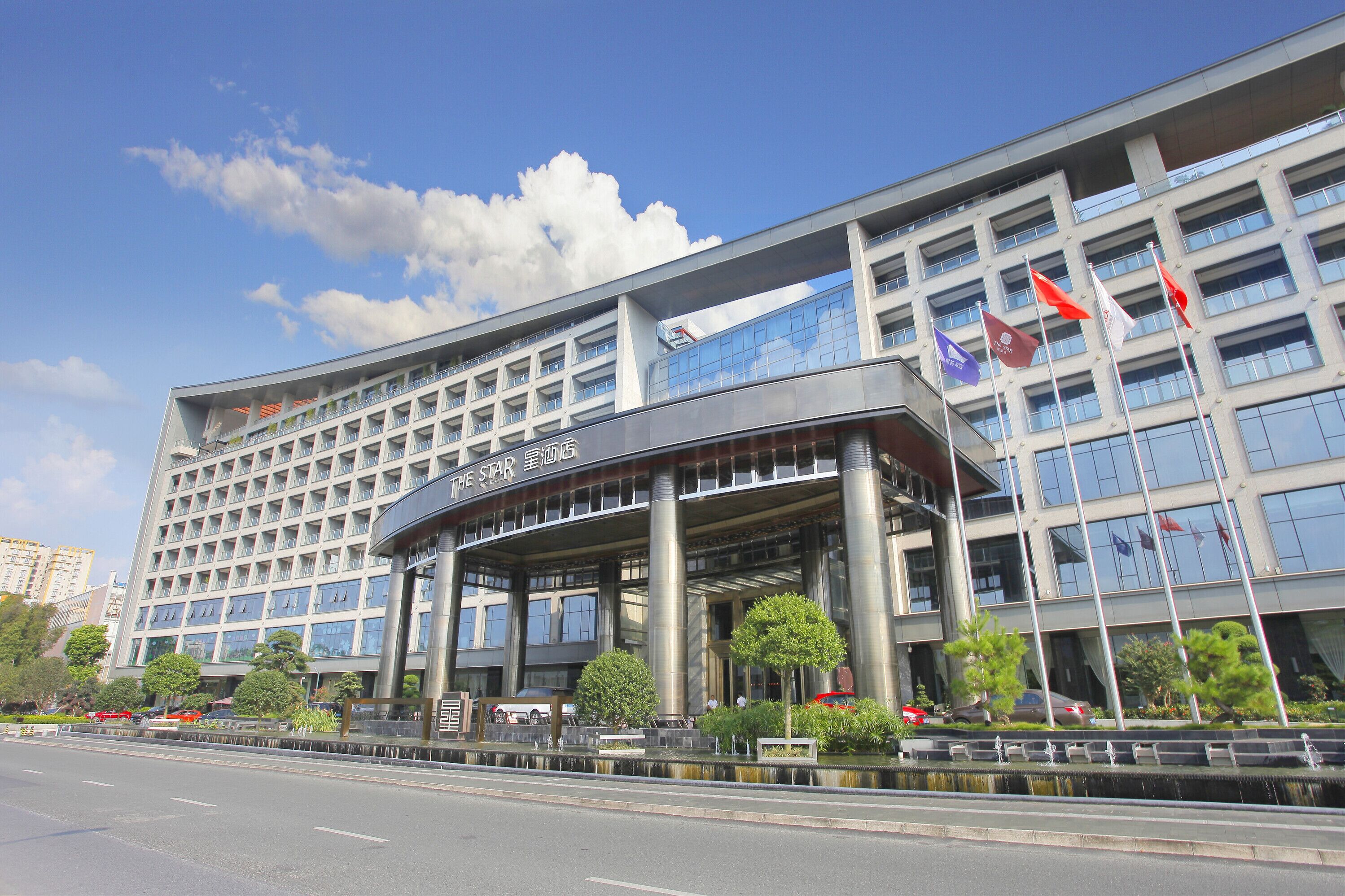 A modern hotel with a curved entrance, multiple floors, and a glass facade.