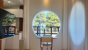 Un intérieur moderne avec une fenêtre ronde donnant sur des arbres et un balcon.