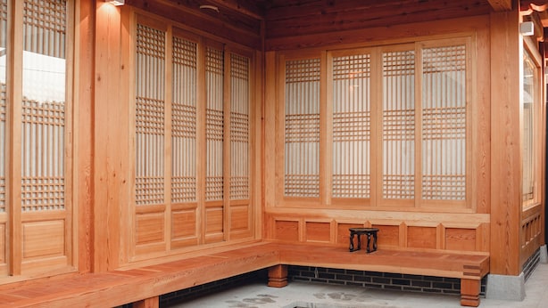 Un bâtiment traditionnel en bois, orné de sculptures complexes, avec un petit banc devant.