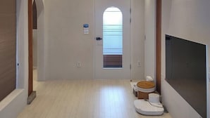 Un couloir avec un plafond en bois, une porte dotée d’une fenêtre et un téléviseur fixé au mur.