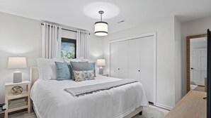 A bedroom with a large bed, two bedside tables with lamps, a wardrobe, and a ceiling light fixture. - 1.5  Miles to Mizzou! ~ Spacious & Updated Home~ (Columbia)