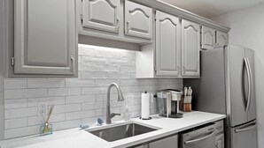 A modern kitchen with grey cabinets, a stainless steel refrigerator, and a white countertop. - 1.5  Miles to Mizzou! ~ Spacious & Updated Home~ (Columbia)