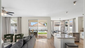 Eine moderne Küche mit eingebautem Geschirrspüler, einem Essbereich mit Tisch und Stühlen sowie einer großen Schiebeglastür, die auf eine Terrasse mit Pool führt.