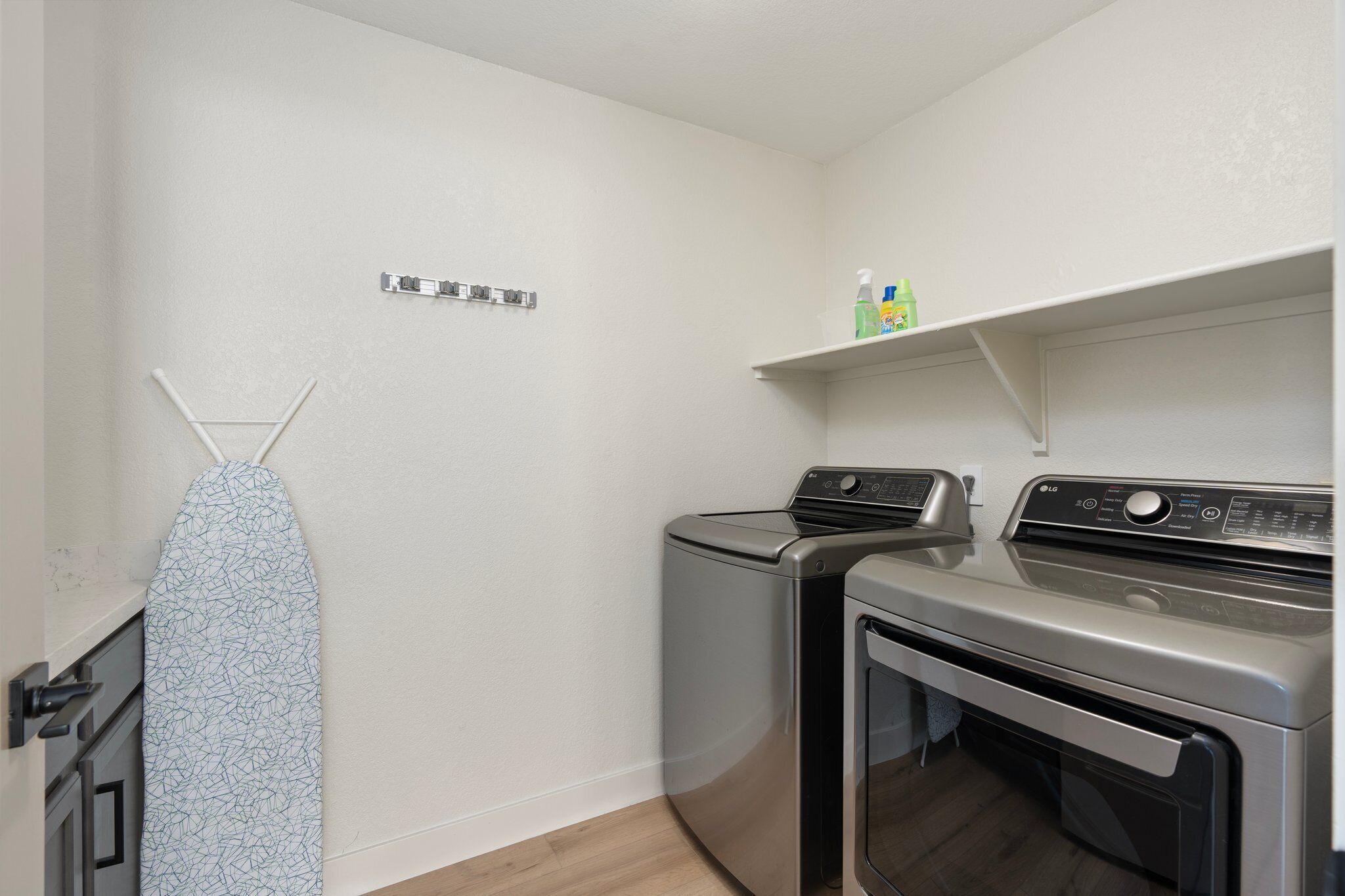 A laundry area with a washing machine, dryer, and ironing board.