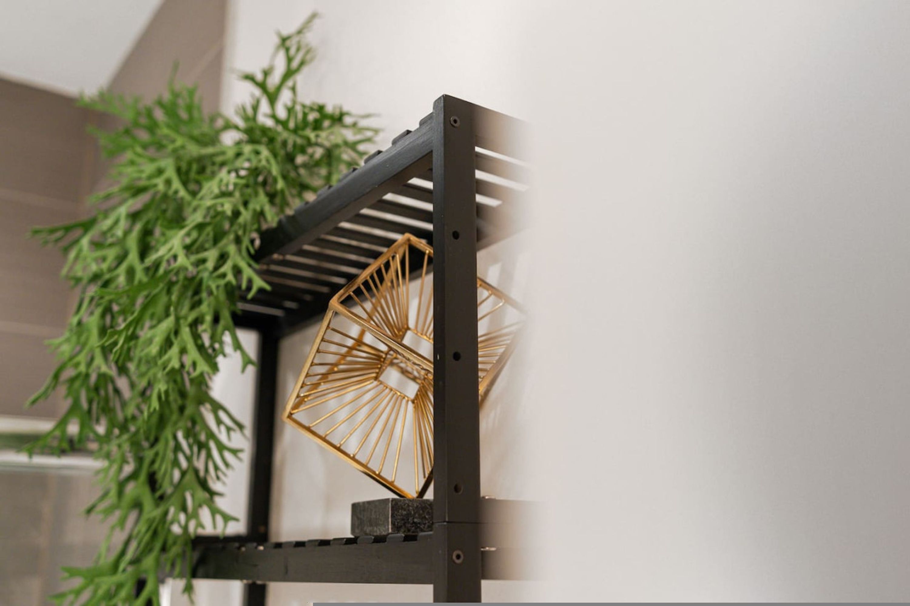 Une étagère en métal au design géométrique, constitué d’une structure en fil de fer, probablement destinée à servir de support pour divers objets.