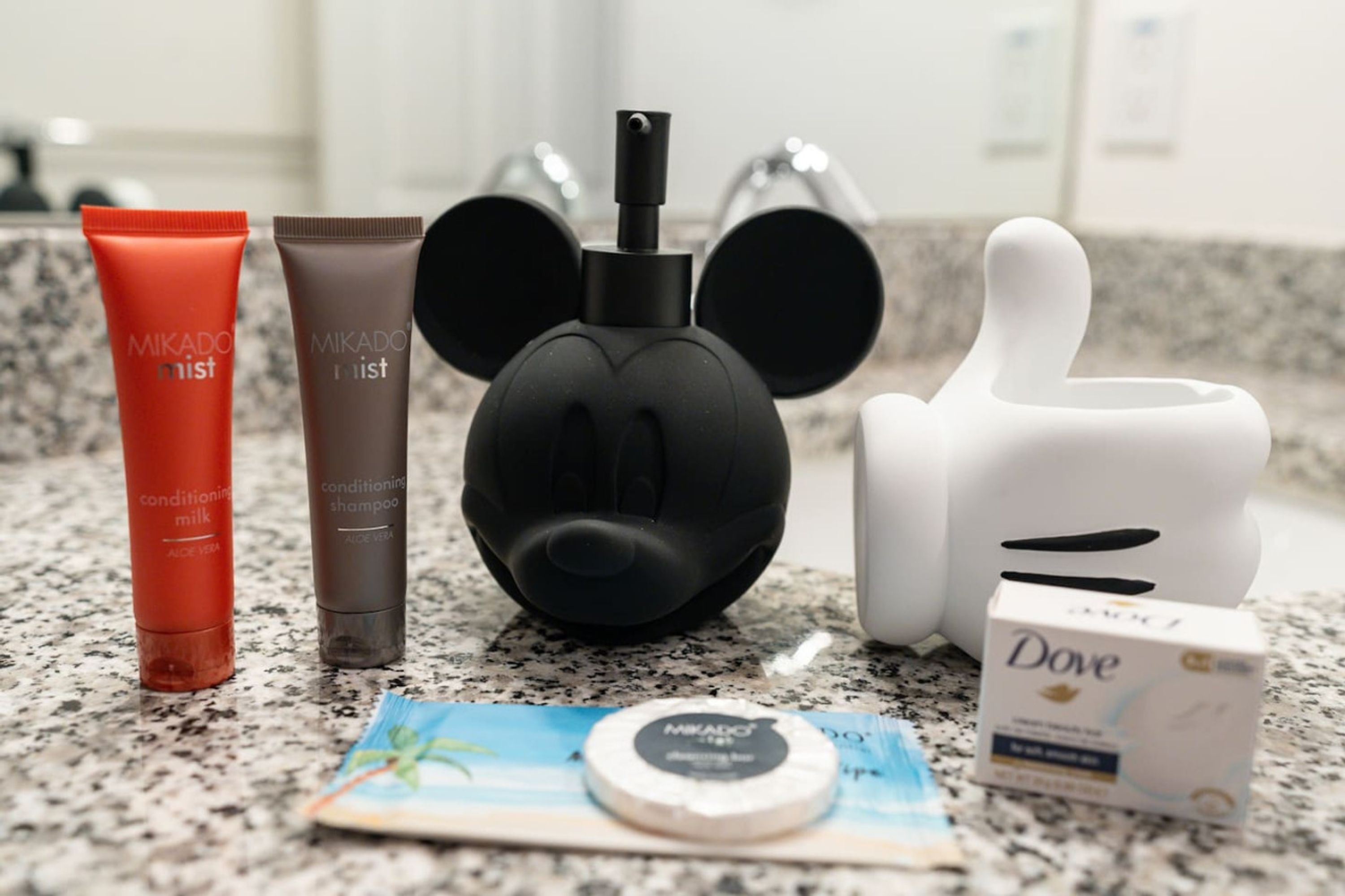 Una encimera de baño con Mikado mist, Mikado list, jabón Dove y un dispensador de jabón con forma de Mickey Mouse.