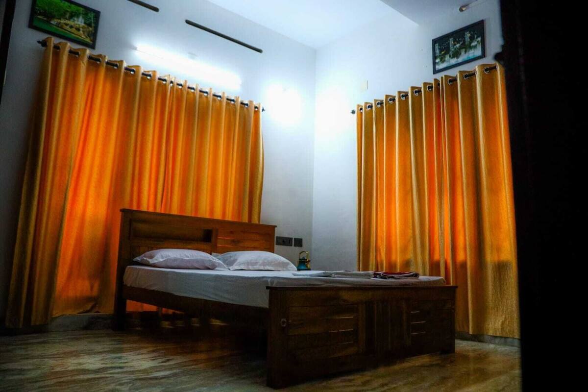A bedroom with a wooden bed, curtains, and a small table.