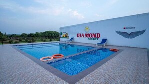 A swimming pool at Diamond Resort with clear blue water, lounge chairs, and a lifebuoy. - VITS Select Diamond Resort Sasan Gir  (Talala)