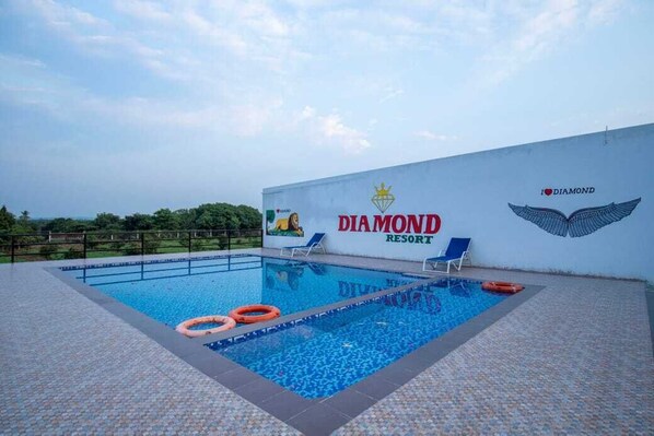 A swimming pool at a resort with a clear sky, a lifebuoy, and a lounge chair.