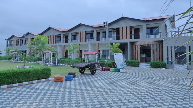 A multi-story hotel with a checkered tile entrance, outdoor seating, and a covered play area. - VITS Select Diamond Resort Sasan Gir  (Talala)