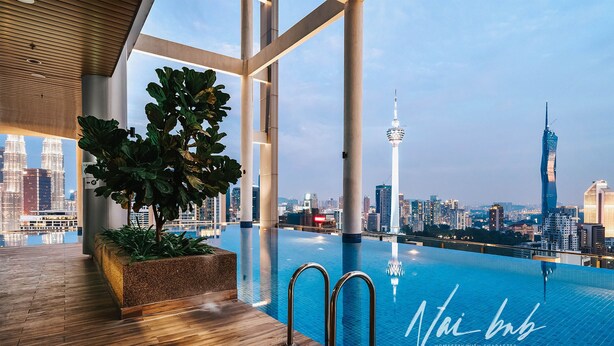 Une piscine intérieure moderne offrant une vue sur les toits de la ville, avec un plancher en bois et une grande plante.