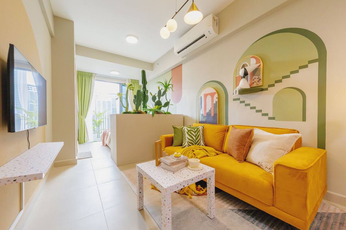 A living room with a yellow sofa, a white coffee table, and a flat-screen TV.