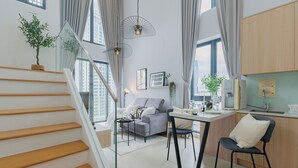 Un appartement moderne doté d’un escalier, d’un espace de vie avec un canapé et une table à manger, et d’une cuisine avec des meubles en bois.