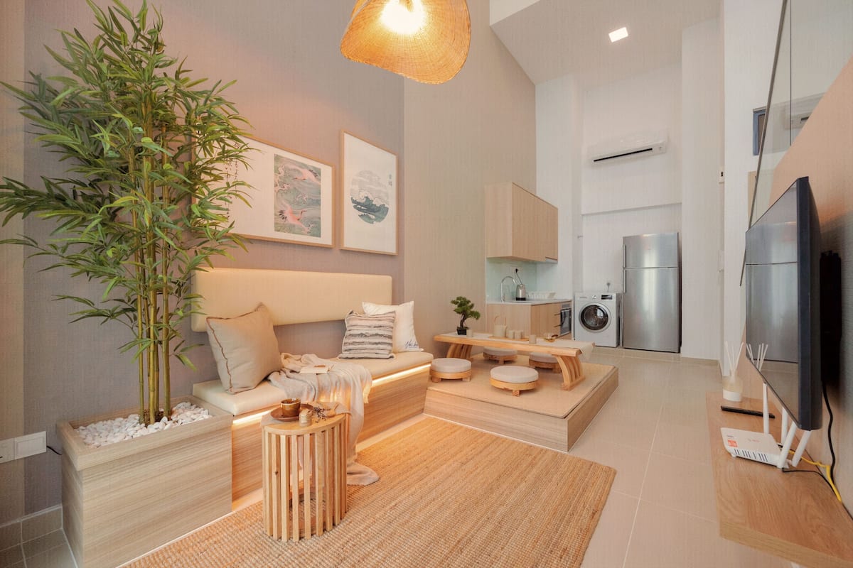 A modern living room with a sofa, a coffee table, a large plant, and a television.