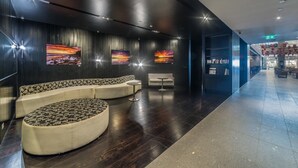 Un hall d’entrée moderne avec un espace salon aux lignes courbes, un comptoir d’accueil et des œuvres d’art accrochées aux murs.