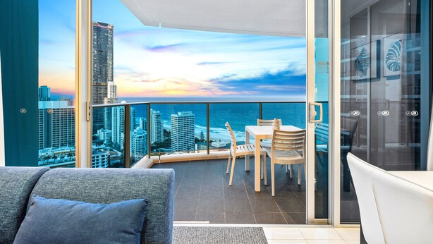 Un balcon avec vue sur la ville, un coin repas avec des chaises et une porte vitrée.
