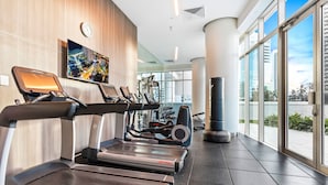 Une salle de sport moderne équipée de tapis de course, de vélos elliptiques et d’appareils de musculation.