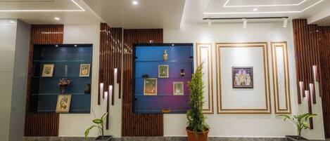 A reception area with a marble floor, framed artwork on the walls, and potted plants.