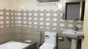 A bathroom with a bathtub, toilet, and sink, featuring patterned tiles and a towel rack. - Hotel Bodhgaya Inn By GRB (Gaya)