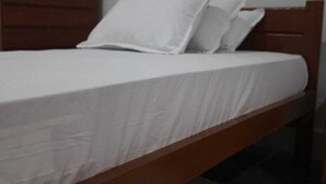 A single bed with white bedding and a wooden headboard in a room with a plain wall. - Hotel Bodhgaya Inn By GRB (Gaya)