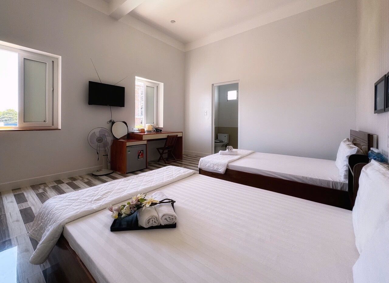 A hotel room with two beds, a desk with a chair, a TV, and a mirror.