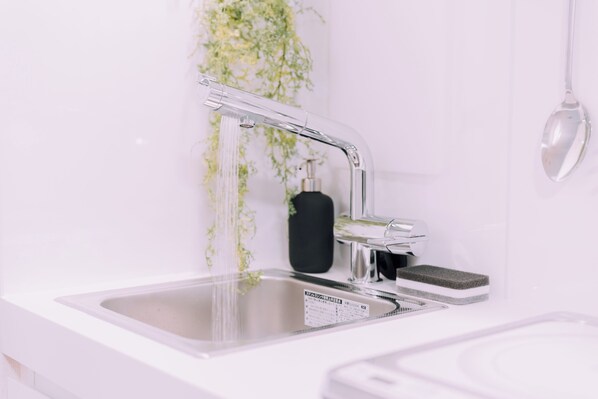 A modern kitchen sink with a faucet, a sponge, and a soap dispenser.