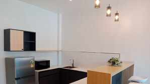 A modern kitchen with a refrigerator, microwave, sink, and bar stools. - Tommy Resort2 (Ko Pha-ngan)