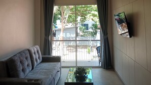 A living room with a sofa, a coffee table, and a TV mounted on the wall. - Tommy Resort2 (Ko Pha-ngan)