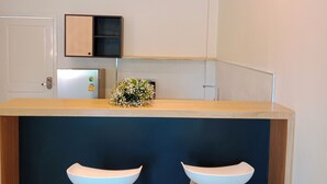 A modern kitchen with a wooden countertop, two white bar stools, and pendant lighting. - Tommy Resort2 (Ko Pha-ngan)