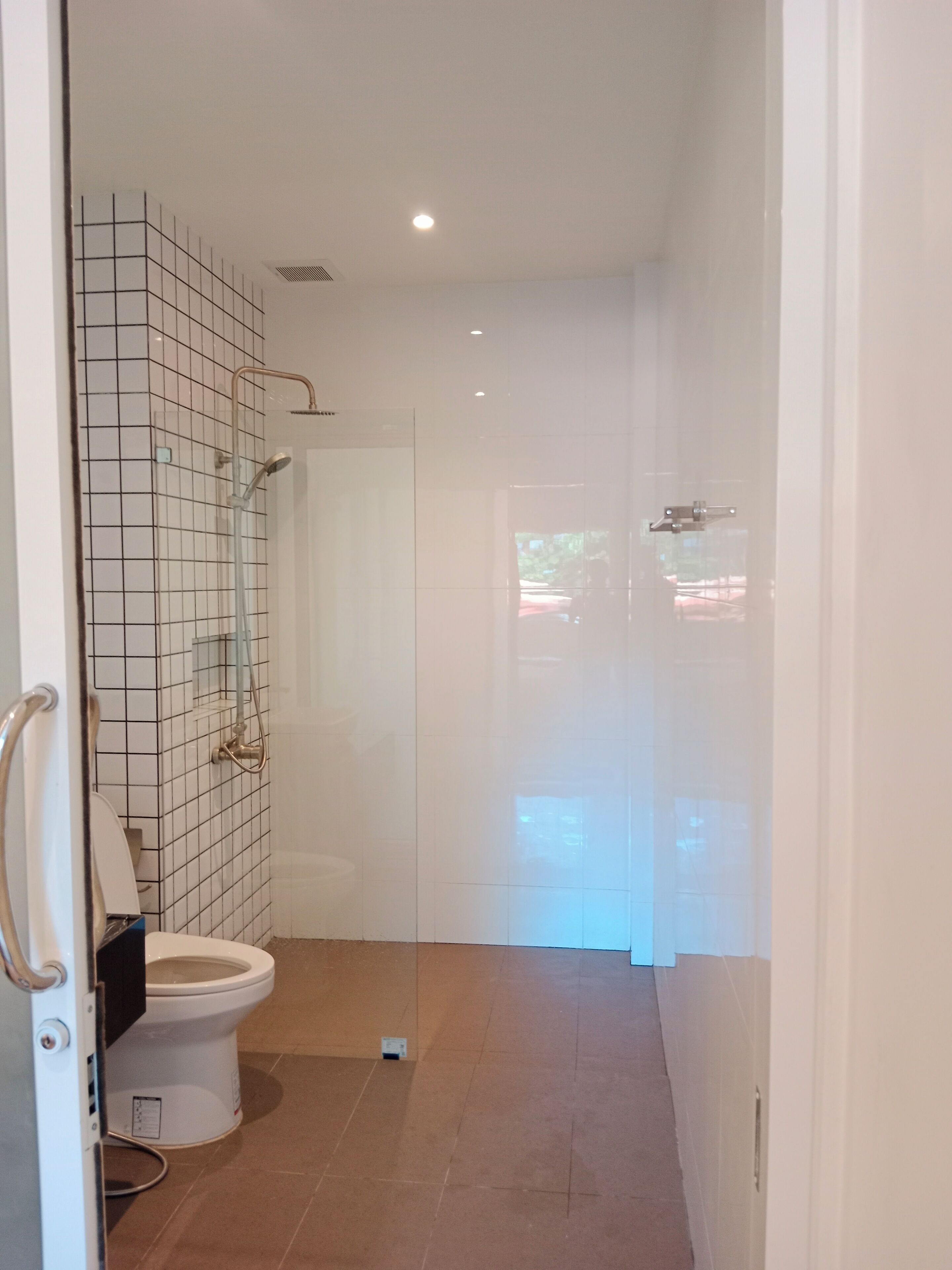 A modern bathroom with a toilet, a shower, and a tiled wall.