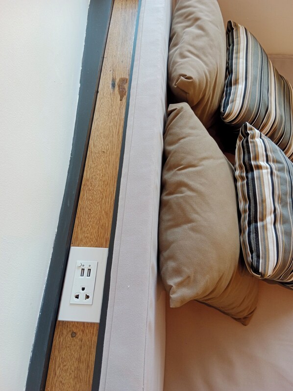 A bed with a wooden headboard, beige pillows, and striped pillows. - Tommy Resort2 (Ko Pha-ngan)