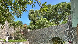 A poolside area with a stone wall, a white chair, and a table with a glass and a metal container.