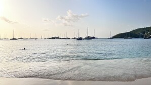 A calm sea with boats and a sandy beach.