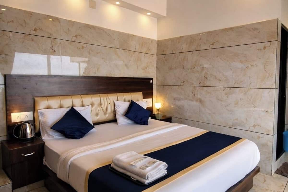 Una habitación de hotel moderna con una cama grande, un ventilador de techo, paredes de mármol y una mesita de noche con lámpara.