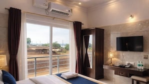 Habitación de hotel con una cama grande, ventilador de techo, aire acondicionado, televisión y vistas al exterior.