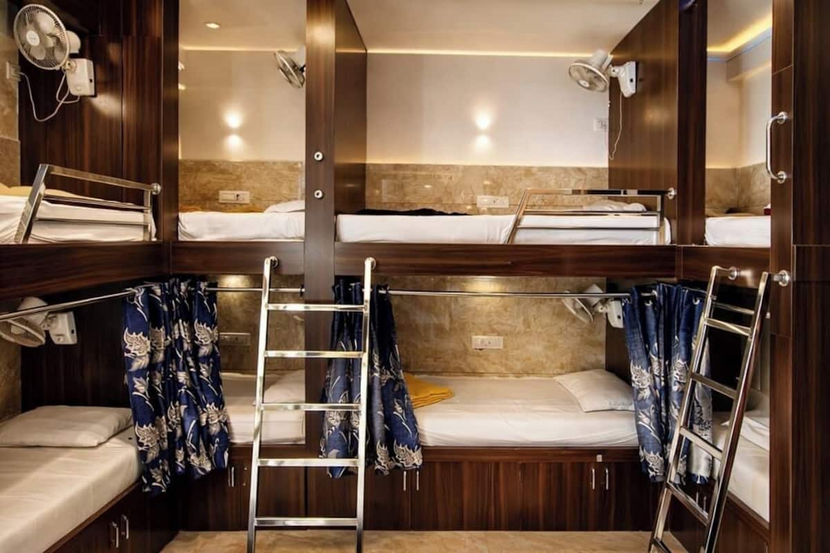 Una habitación compacta y bien iluminada, con literas, una pequeña zona de estar y un ventilador.