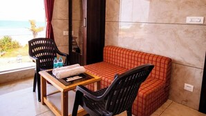 Habitación con sofá, dos sillas, una mesa, un armario y vista al mar.