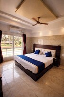 A large bed with a wooden headboard, a ceiling fan, and an air conditioning unit.