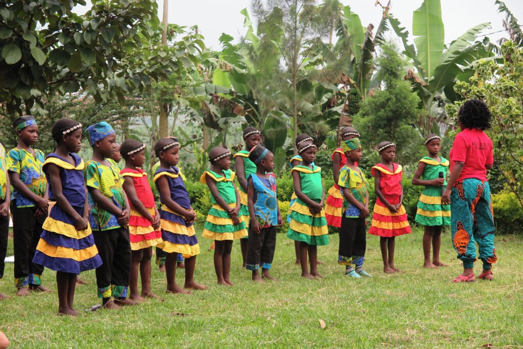 Een groep kinderen in kleurrijke, traditionele kleding staat in een rij buiten.