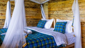 Ein Schlafzimmer einer Holzhütte mit einem Bett, weißer Bettwäsche und blau karierten Decken.