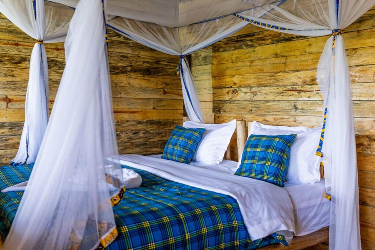 Ein Schlafzimmer einer Holzhütte mit einem Bett, weißer Bettwäsche und blau karierten Decken.