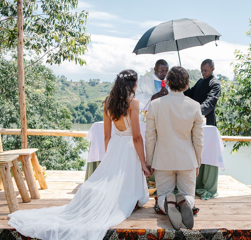 A wedding ceremony on a wooden deck with a view of a lake and hills.