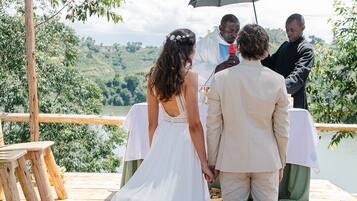 A wedding ceremony on a wooden deck with a view of a lake and hills.
