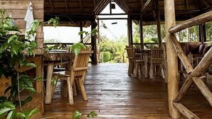 Eine Holzterrasse mit rustikalen Möbeln und einer Reetdachkonstruktion.